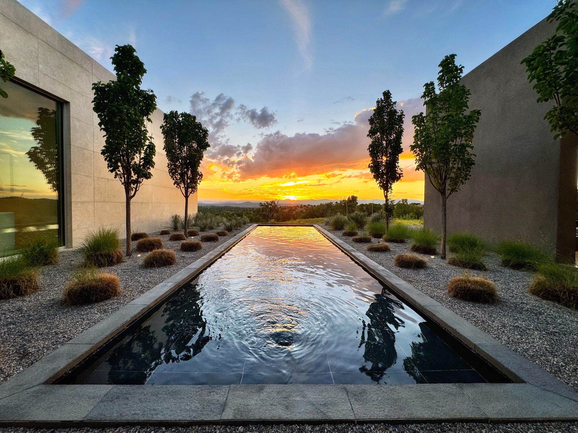 Paseo del Conejo courtyard reflecting pool at sunset, framed by columnar trees